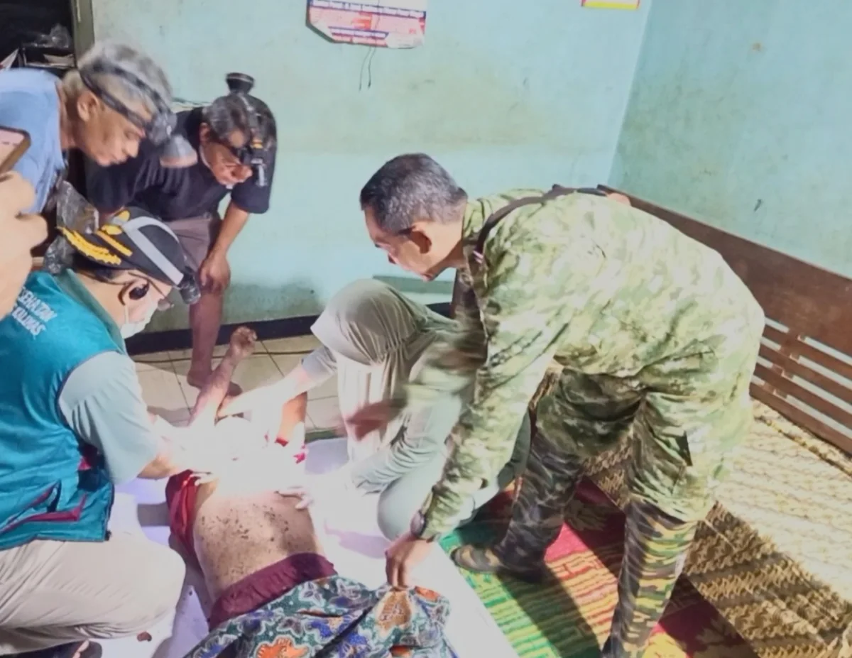 Korban sedang diperiksa oleh tenaga kesehatan, didampingi aparat dari TNI